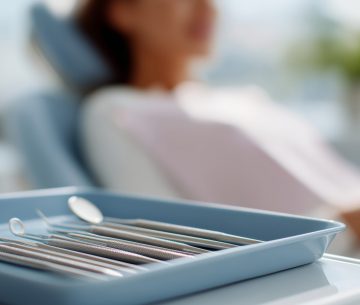 419550719 Tools prepared for dental examination in a modern clinic as a patient relaxes in the dental chair during a sunny day
